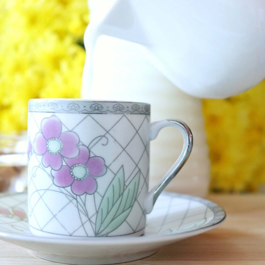 Delicious homemade almond milk. Pouring the milk in a lovely cup. Bright yellow flowers and a bottle of freshly made almond milk is the background.