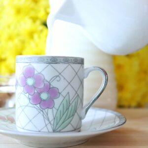 Homemade almond milk recipe with raw organic almonds and fresh water. Sweetened with agave syrup. Pouring almond milk in a small cup with bright yellow flowers and a bottle of fresh milk in the background.