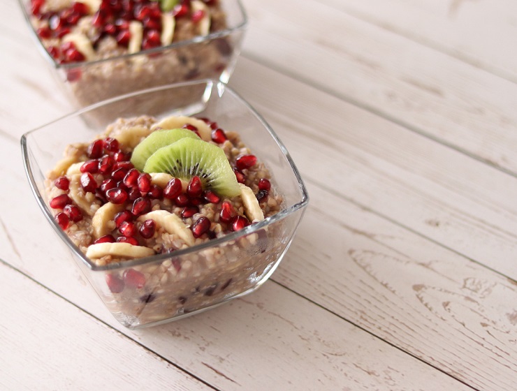 Healthy kasha decorated with fresh pomegranate seeds and kiwi on a wooden background