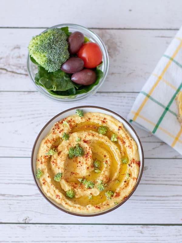 Delicious hummus drizzle with olive oil on wooden table with veggies