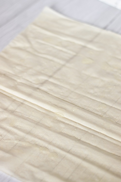 filo dough sheet on wooden table sprinkled with dressing.