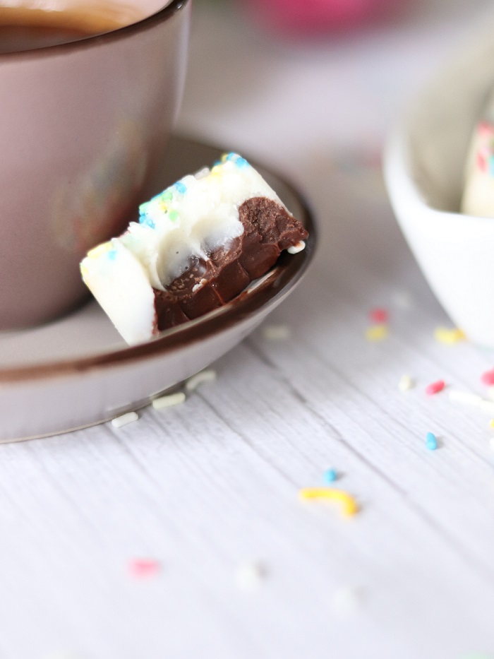 A piece of homemade chocolate heart besides coffee cup on wooden table. Easy dessert idea at home.