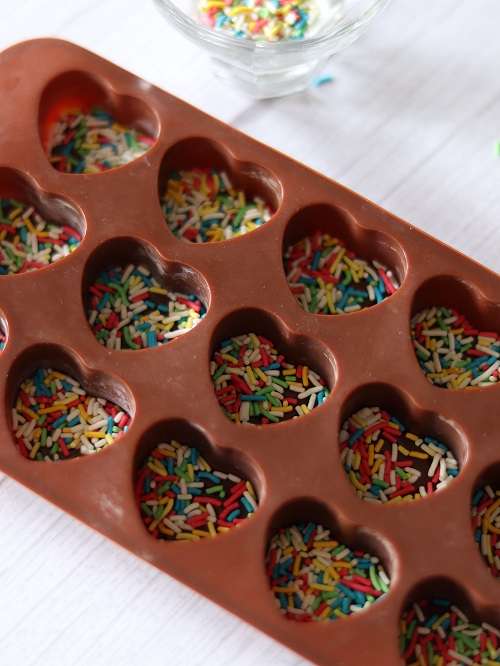 Rainbow sprinkles spread in silicone heart mold