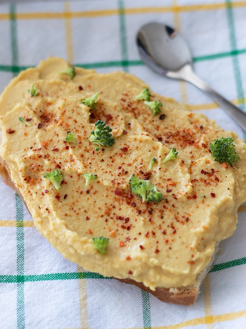A slice of homemade bread spread with hummus made without tahini 