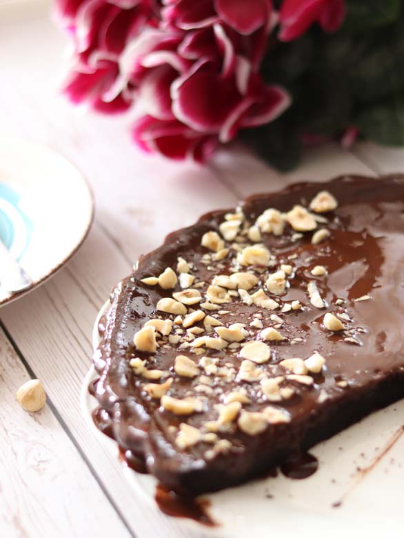 Homemade chocolate cake for dessert. Dairy-free and egg-free. Rich chololate vegan cake covered with chopped hazelnuts.