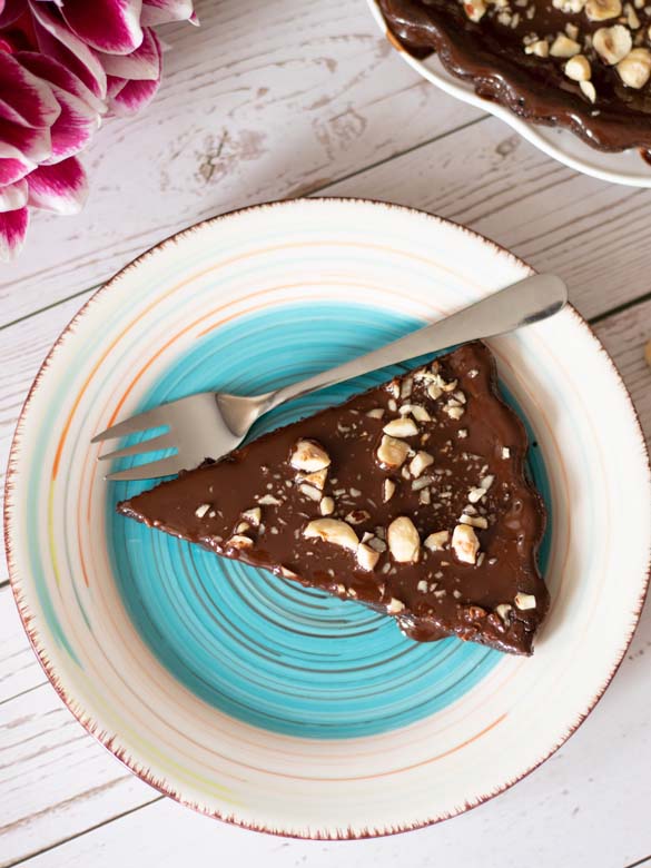 A piece of homemade chocolate cake covered with melted chocolate and chopped hazelnuts for dessert