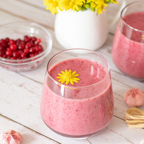 Cranberry banana raspberry creamy smoothie recipe decorated with yellow flower