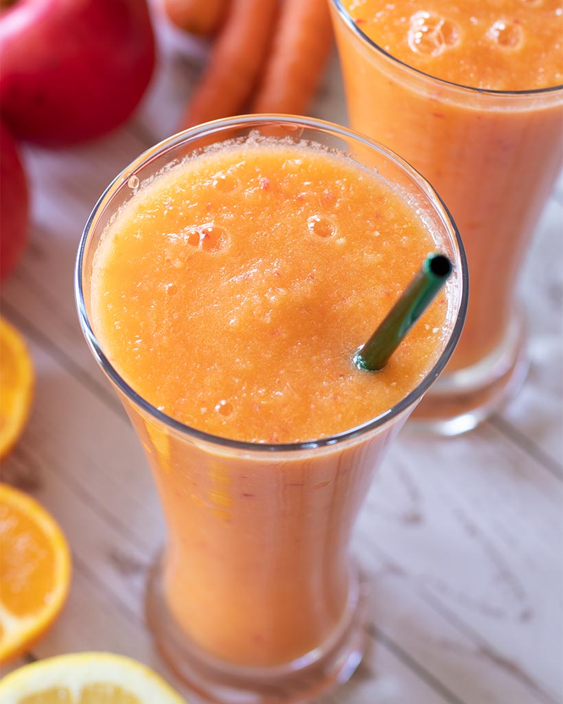 Vibrant orange carrot apple smoothie that tastes good. Yummy vegan drink without banana. Non dairy plant based beverage. 