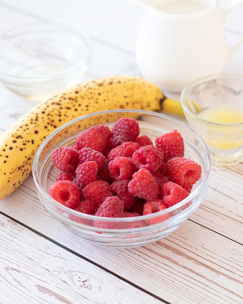 Wholesome real food ingredients for making raspberry smoothie recipe: fresh raspberries, banana, almond milk, agave syrup and lemon juice.