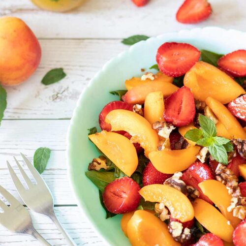 Fresh summer salad with apricots, strawberries, spinach and walnuts and lemon-orange-min vinaigrette dressing
