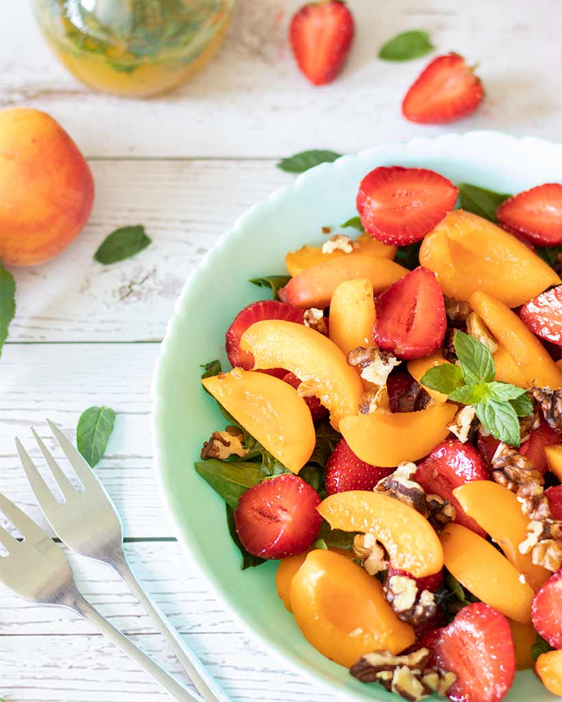 Fresh summer salad with apricots, strawberries, spinach and walnuts and lemon-orange-min vinaigrette dressing