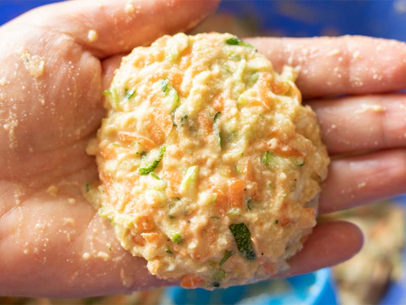 Female hand holding homemade batter formed into a pattie prepared for frying