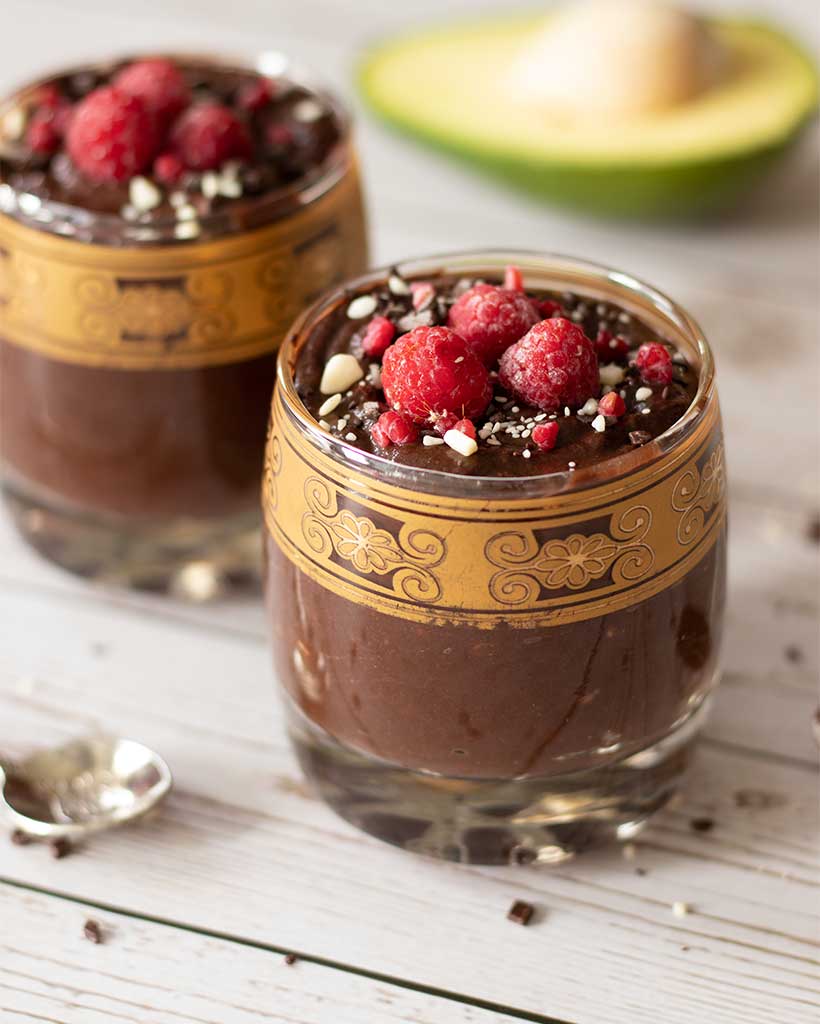 Two glasses with raw chocolate mousse with raw cacao powder,  creamy avocados, and plant-based milk. Healthy dessert idea for kids and adults.