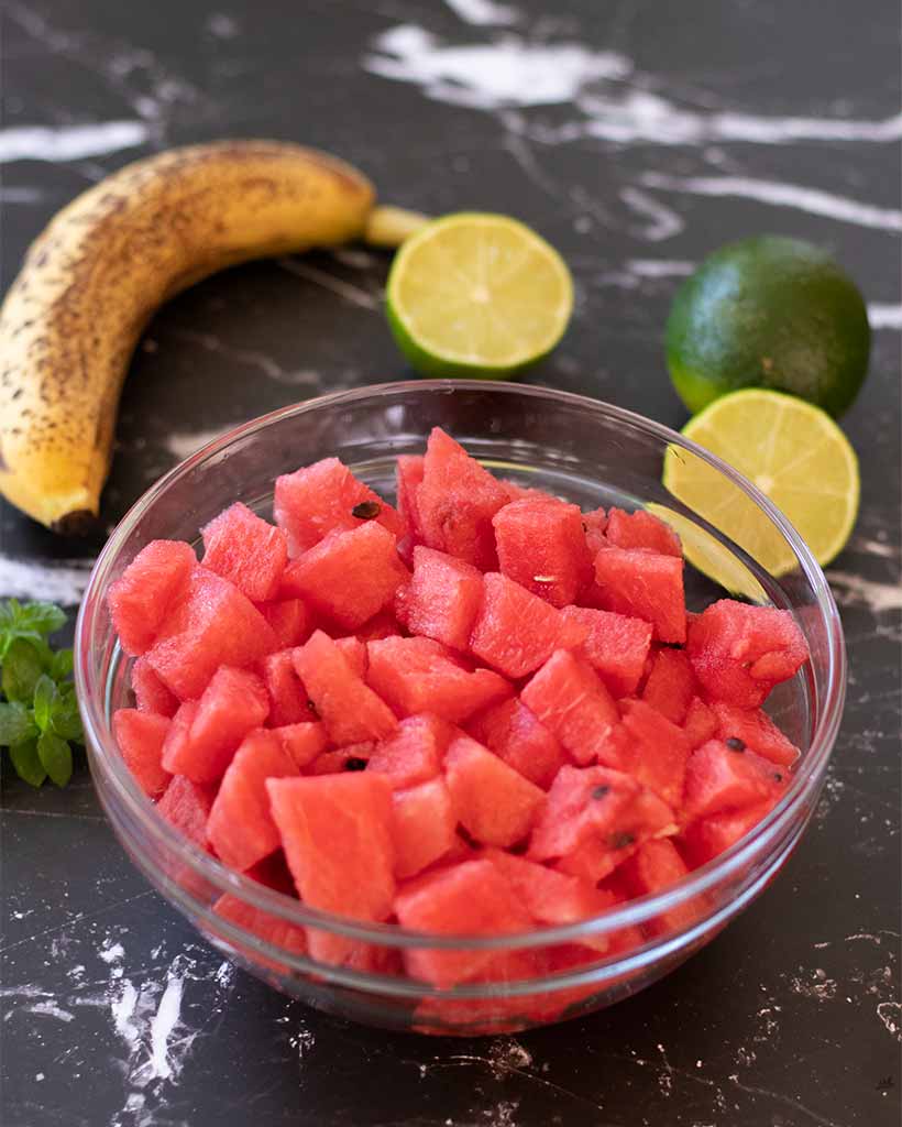 Whole food ingredient for preparing easy watermelon smoothie recipe: fresh watermelon, banana, lime and mint leaves.