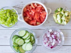 Fresh chopped vegetables (tomatoes, cucumbers, red onion, Shishito peppers and avocado) for preparing healthy, plant-based, gluten free salad