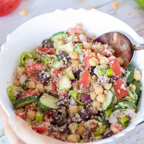 Mediterranean quinoa salad with chickpeas and various colorful veggies (cucumber, tomatoes, red onion, avocado and olives) drizzled with simple olive oil-mustard dressing.