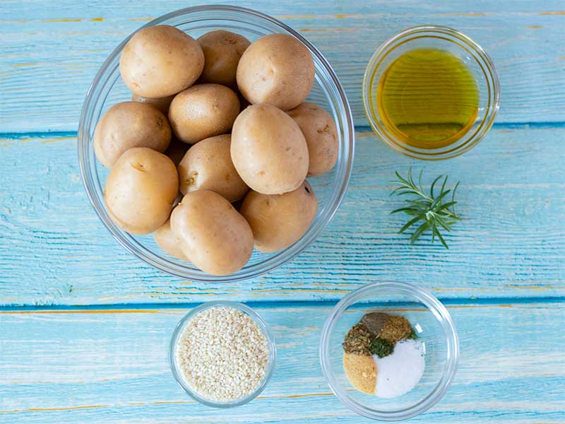 Plant-based, wholesome minimal ingredients new baby potatoes recipe for lunch or dinner: small potatoes, olive oil, fresh rosemary, spices and herbs..