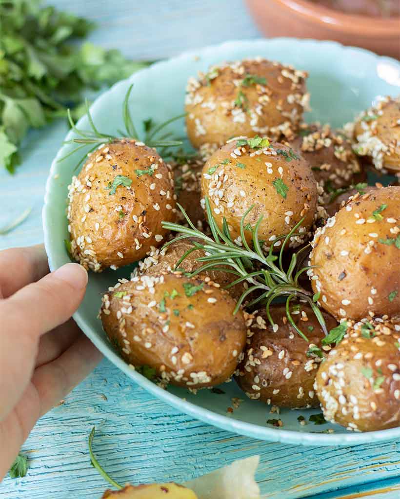 Crispy, golden new potatoes with rosemary, sesame seeds and other herbs for healthy, vegan or vegetarian side dish. Kid friendly meal prep.