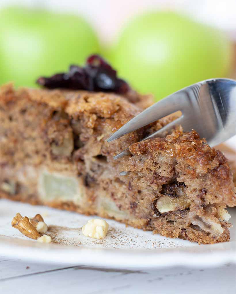Fork cuts a piece of eggless apple cinnamon cake for breakfast or dessert. Easy and healthy sweet treat for kids.