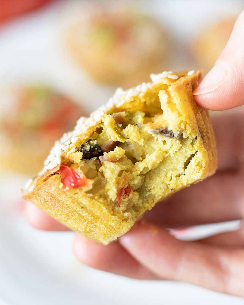 Vegan egg-free mini frittata muffin in woman's hand. Gluten-free, dairy-free and allergy friendly snack loaded with wholesome veggies.