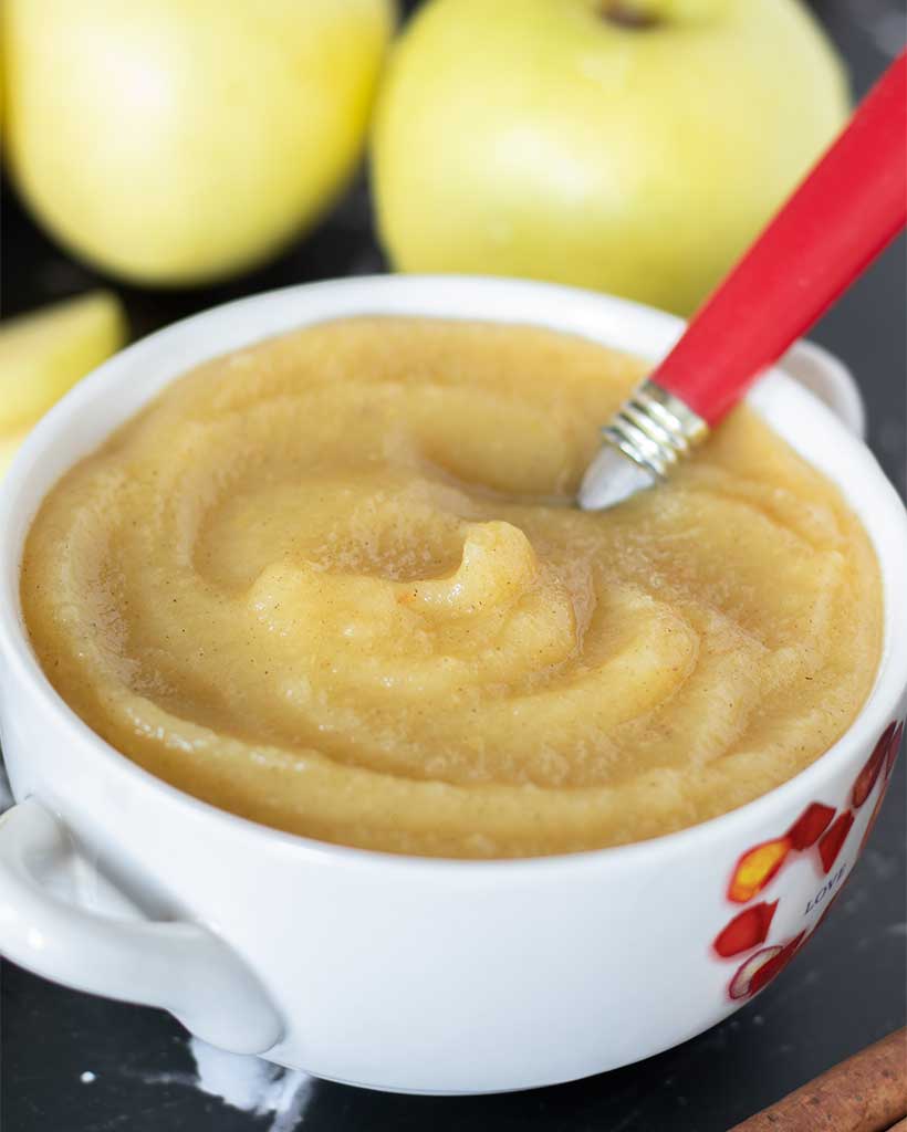 Healthy homemade applesauce in a small bowl with a spoon. Delicious and easy to make snack or dessert without sugar.