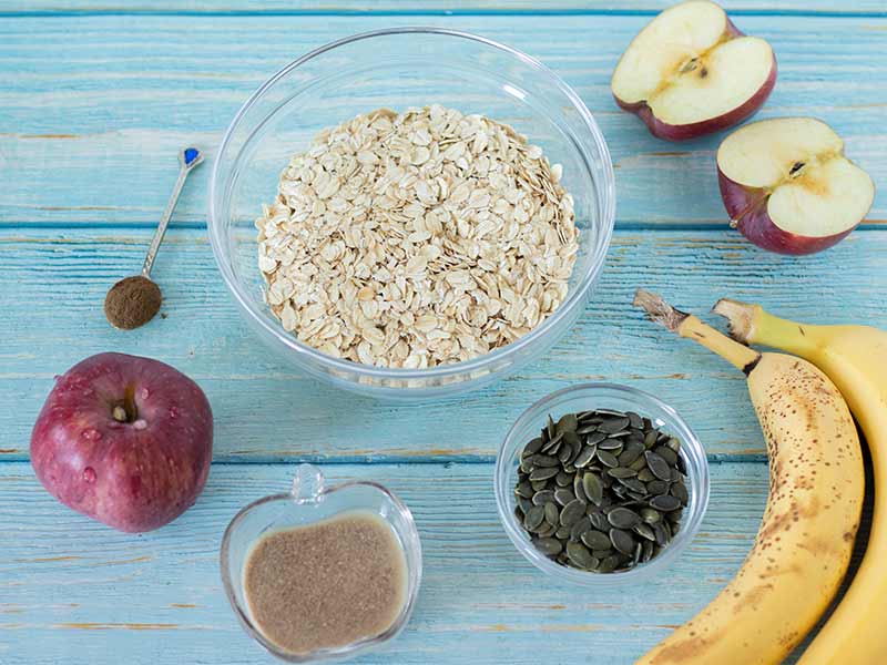 Simple and wholesome ingredients for baking delicious and soft apple cookies with pumpkin seeds: red Delicious, oats, bananas, pumpkin seeds, cinnamon and homemade flax egg.