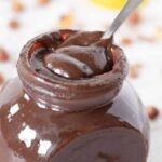 Recipe for homemade Nutella. Best vegan hazelnut spread in a glass jar with spoon.