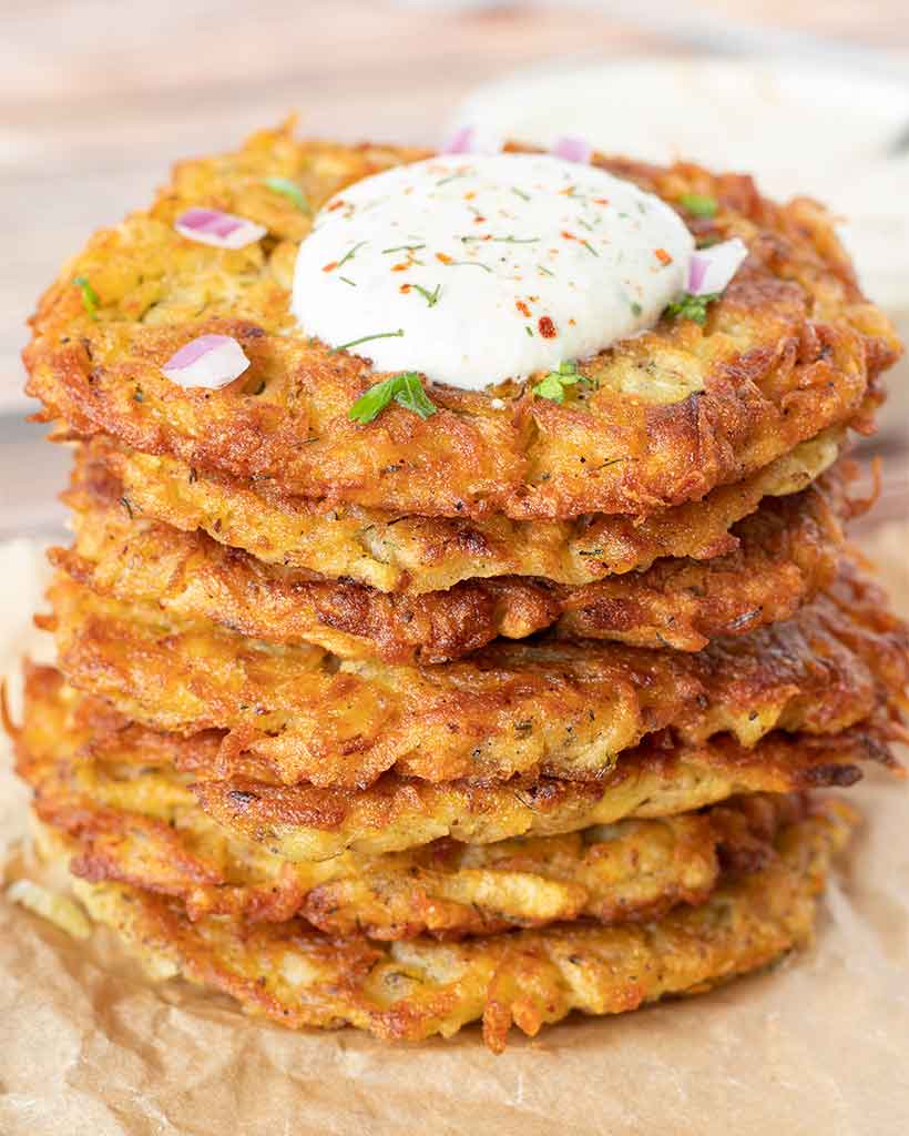 A stack of plant-based potato latkes served with creamy vegan ranch dressing.