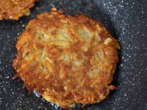 Perfectly crispy, golden-brown latke in a frying pan.
