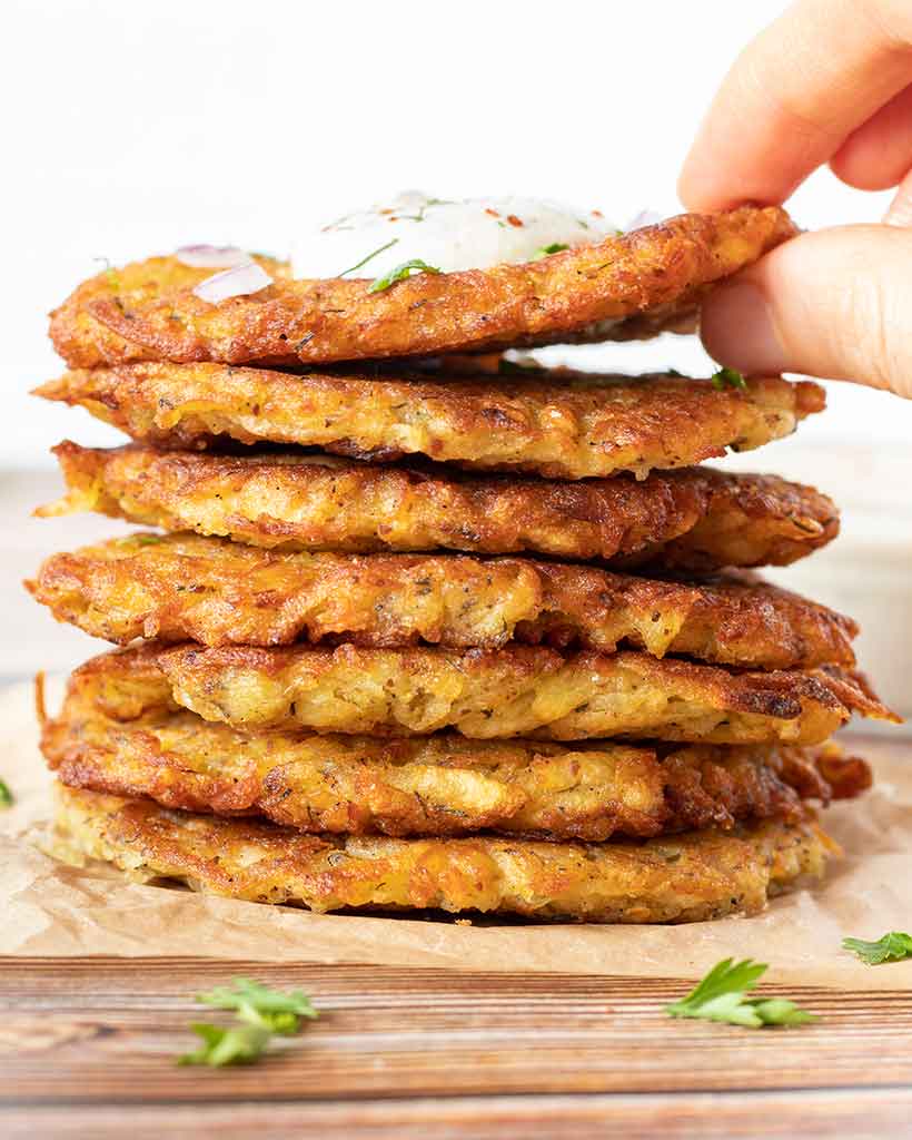 A stack of crispy and delicious vegan potato fritters topped with simple, homemade ranch dressing for side dish, snack, appetizer or starter.