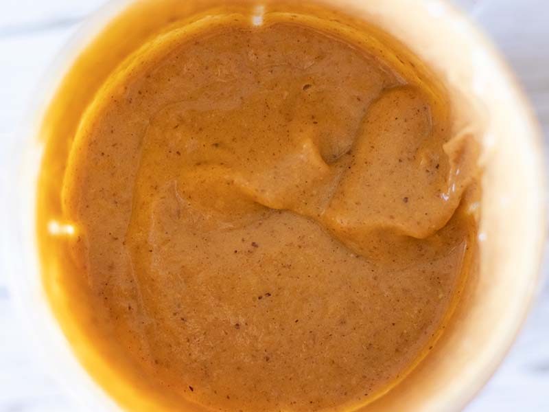 Blended smooth and creamy pumpkin puree smoothie in a glass for quick on-the-go breakfast or snack.