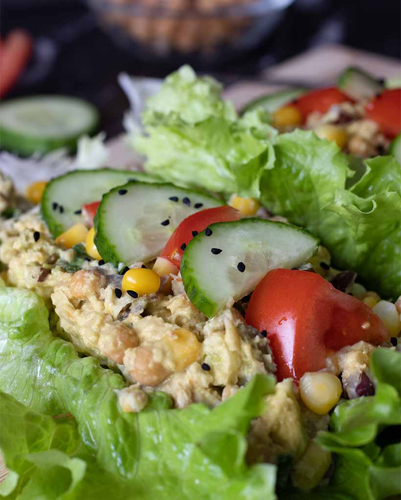 Best and simple high-protein chickpea spread  used as a filling for lettuce wraps topped with fresh cucumbers, tomatoes and black seeds.