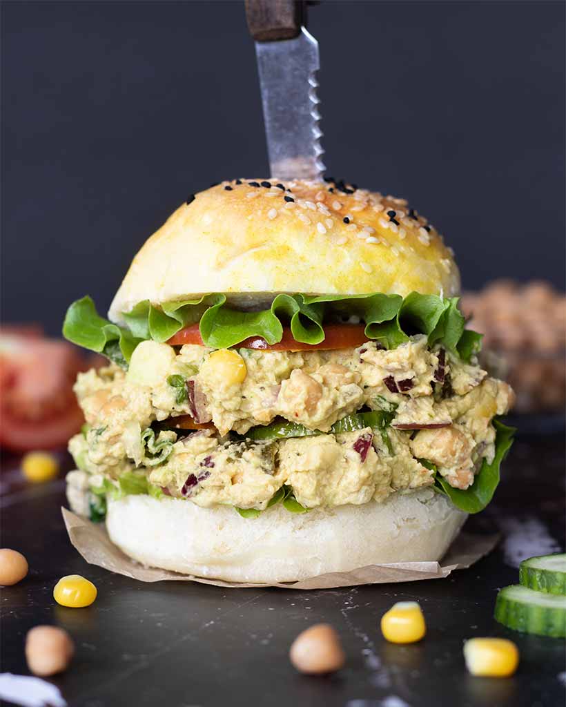 Chickpea vegan tuna salad with avocado and healthy vegetables spread on a homemade sandwich with fresh lettuce and tomato