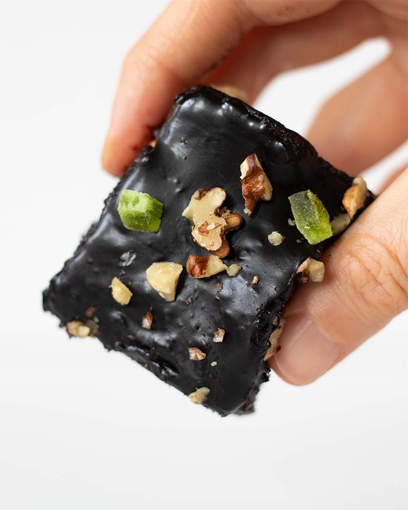 A square of no-bake homemade vegan brownie in woman's hand.