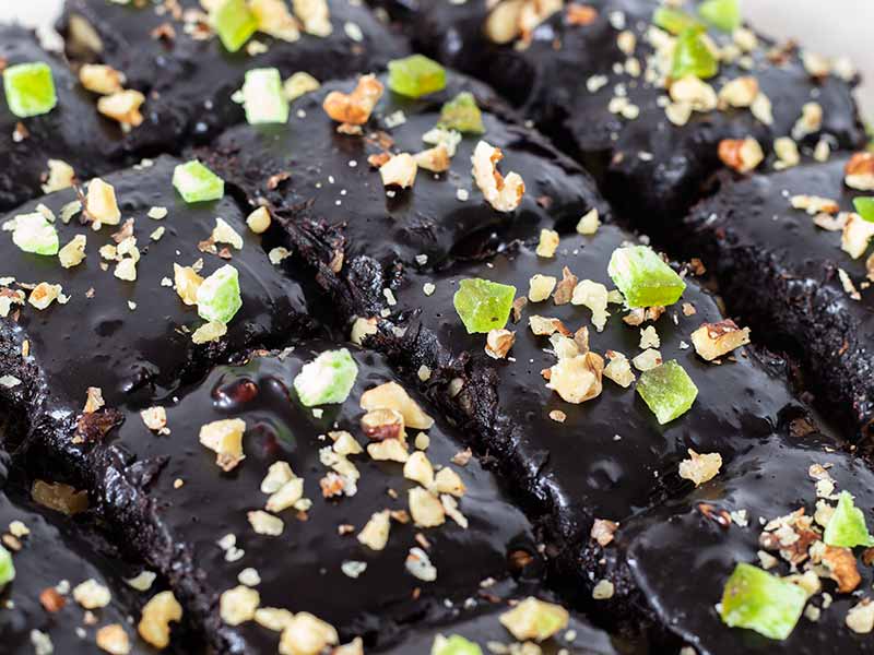 No-bake vegan brownies with chocolate ganache decorated with finely chopped walnuts and pomelo peel. Quick and easy gluten-free, flourless, eggless dessert or snack.
