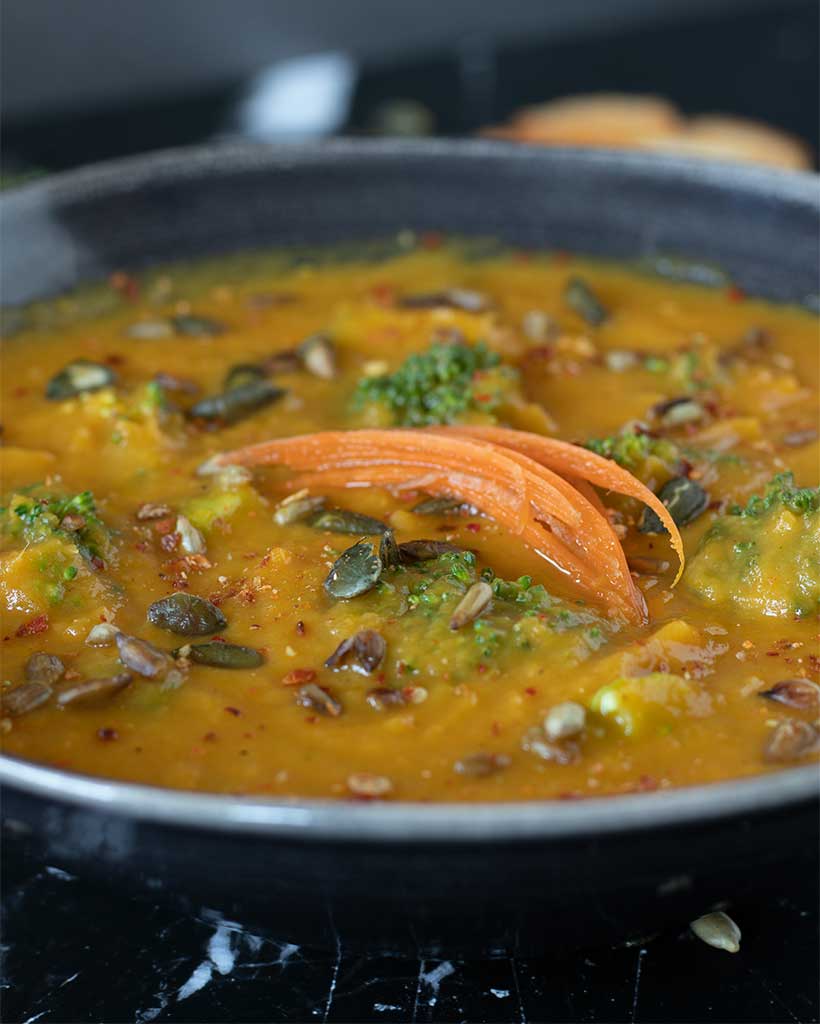 Creamy and healthy carrot and parsnip soup recipe topped with roasted pumpkin seeds, sunflower seeds, and julienned carrots as an easy side dish for lunch or dinner.