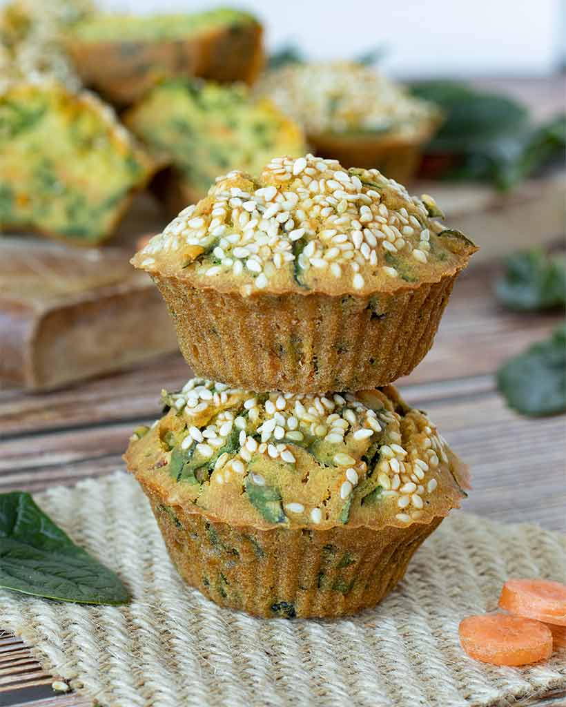 Two savory breakfast muffins with spinach on wooden table as and easy make-ahead breakfast or lunch box snack for school or work.
