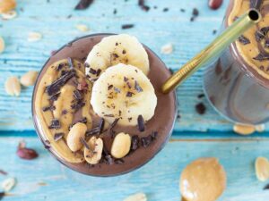 Creamy weight-loss friendly chocolate smoothie in a glass on blue wooden table.