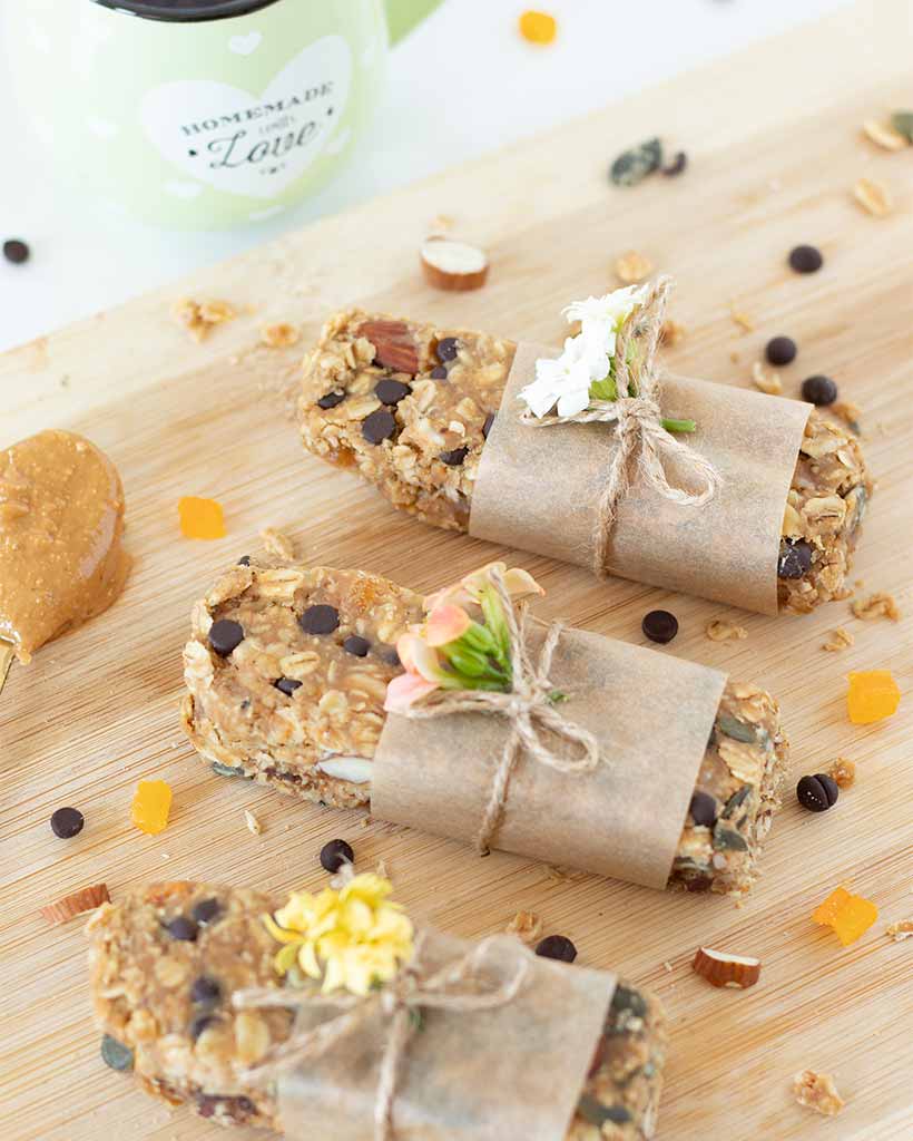 Homemade no-bake energy bars with peanut butter and chocolate chips wrapped in a parchment paper with flowers for kids snack or dessert..