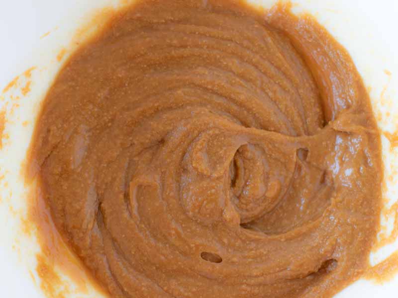 Creamy batter form peanut butter, maple syrup and vanilla extract for preparing raw vegan energy bars at home.