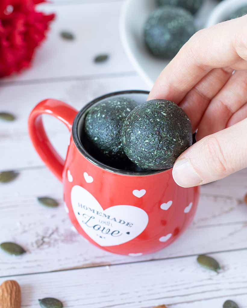 Spirulina snack balls with dates in a small red pot. Delicious protein pre or post workout bites.