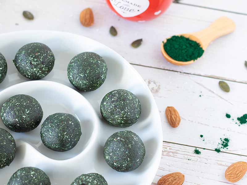 Sweet vegan energy balls in a plate on wooden table. Kid-friendly, dairy-free make ahead recipe without refined sugar or oil.