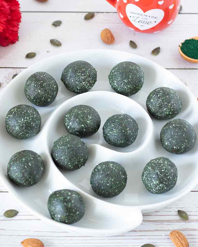 A plate full of vegan spirulina energy balls made without sugar. Dairy-free, gluten-free, refined sugar-free snacks.