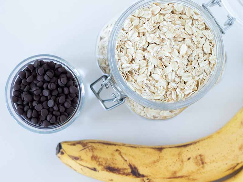Simple plant-based ingredients (banana, rolled oats, dairy-free chocolate chips) for baking wholesome breakfast cookies.