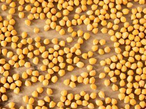 Cooked chickpeas in a baking pan covered with parchment paper.