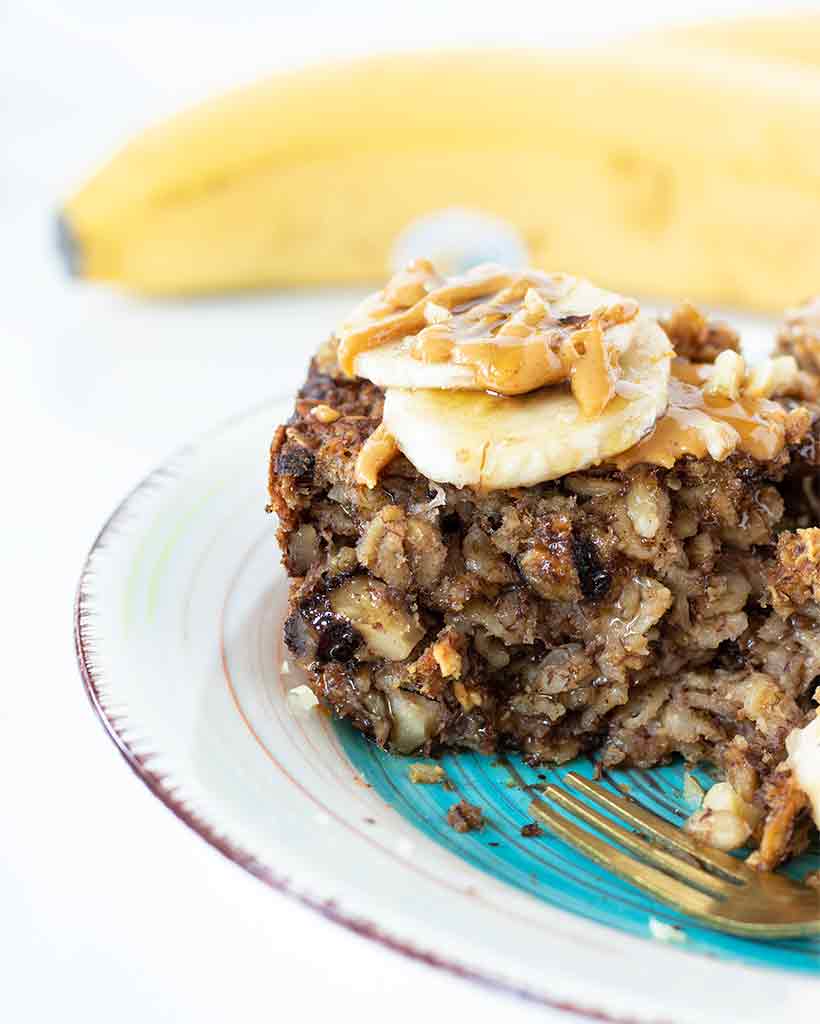 Healthy vegan banana bread baked oatmeal for breakfast topped with sliced bananas and creamy peanut butter.