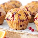 Moist vegan cranberry orange muffins on a wooden board for a healthy breakfast or snack