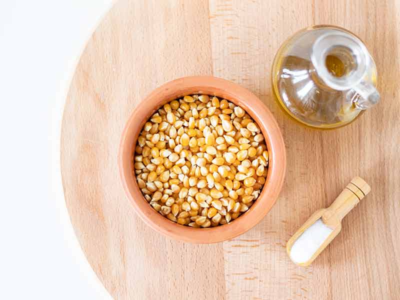 Budget-friendly, vegan ingredients for cooking homemade popcorn recipe: corn kernels, extra virgin olive oil, and fine sea salt.
