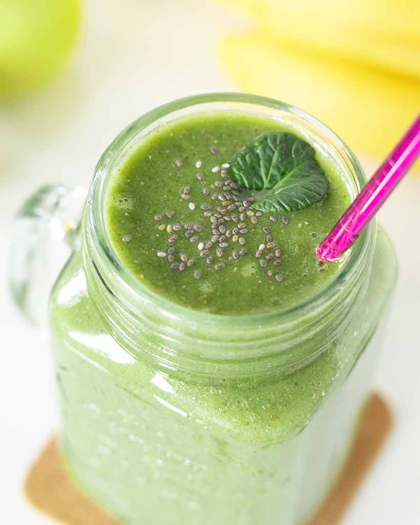 Tasty weight-loss green spinach smoothie with banana and apple in a glass