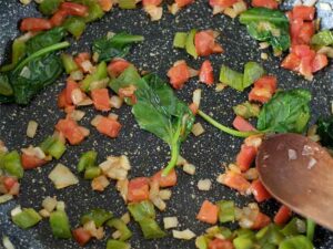Vegetables in a frying pan for preparing plant-based eggless scramble with chickpea flour